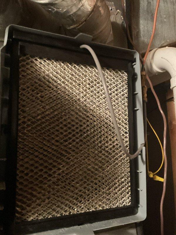 Responded to service call regarding humidifier malfunction following previous technician visit. Upon inspection, accessed furnace cabinet and examined humidifier system components including water supply lines, humidifier pad, and electrical connections. Humidifier pad appeared to be in serviceable condition within its black mounting frame. Verified proper installation of evaporator pad and checked water supply plumbing connections. Documented system configuration and current state of equipment for service records.
