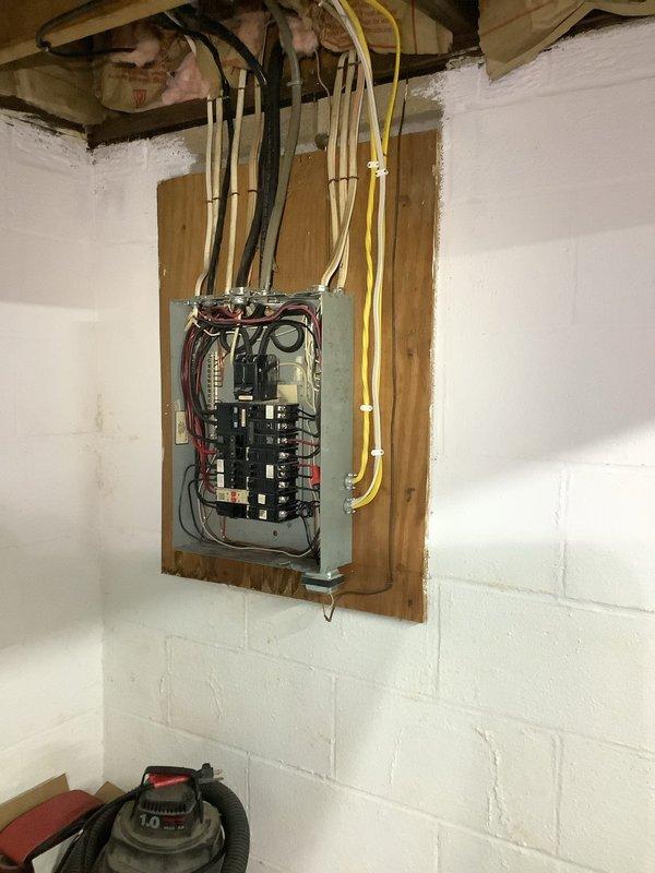 Conducted electrical estimate for 200-amp panel upgrade in basement. Evaluated existing electrical panel mounted on wooden board against concrete block wall, assessed current breaker configuration and wire routing through ceiling joists, and inspected exterior meter base and service entrance equipment. Provided comprehensive assessment and pricing for complete service upgrade including new 200-amp main panel, proper grounding, and code-compliant installation.