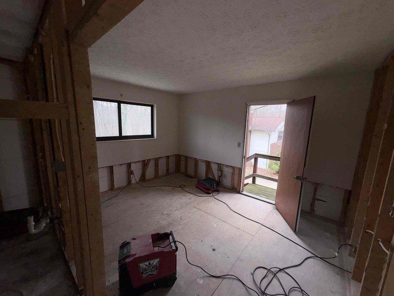 Conducted comprehensive site assessment of residential property following catastrophic flood damage. Property had been gutted by mitigation company with complete removal of interior finishes down to wall studs and subfloor. Evaluated requirements for full HVAC system replacement, electrical rewiring, and hot water heater installation. Documented existing exterior utility connections and deteriorated equipment mounting locations on building exterior. Assessed ductwork replacement needs throughout structure. Coordinated entry access through garage door as primary entrance point during evaluation phase.