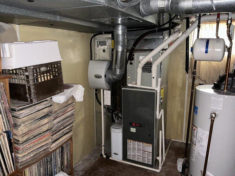 Provided comprehensive estimate for replacement of 13-year-old gas furnace with cracked heat exchanger and air conditioning system with low refrigerant due to stuck Schrader core valve. Documented existing equipment condition in basement mechanical room and exterior condenser unit location. Presented options for complete HVAC system replacement to address multiple critical component failures requiring extensive repairs.