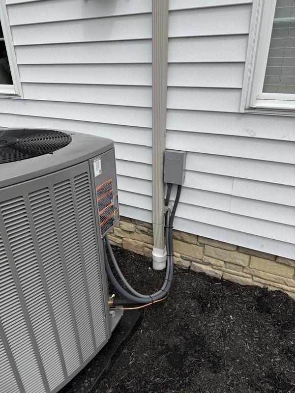 Completed installation of new air conditioning system and humidifier at residential property. Installed outdoor condenser unit on prepared mulch bed with proper clearances, ran refrigerant lines and electrical conduit to disconnect box mounted on exterior wall, and installed condensate drain line. System was evacuated to proper micron level as verified by vacuum gauge reading, pressure tested, and commissioned for operation.