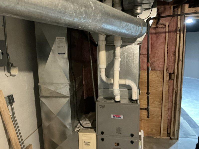 Completed HVAC system estimate for replacement of existing furnace unit installed in October 2003, as indicated by handwritten notation on ductwork. Assessed beige/tan gas furnace with connected white PVC venting pipes and galvanized sheet metal supply ductwork in unfinished basement utility area. Documented current equipment configuration including manufacturer specifications, system age verification, and existing ductwork layout to provide replacement options excluding builder-grade equipment exceeding specified budget parameters.