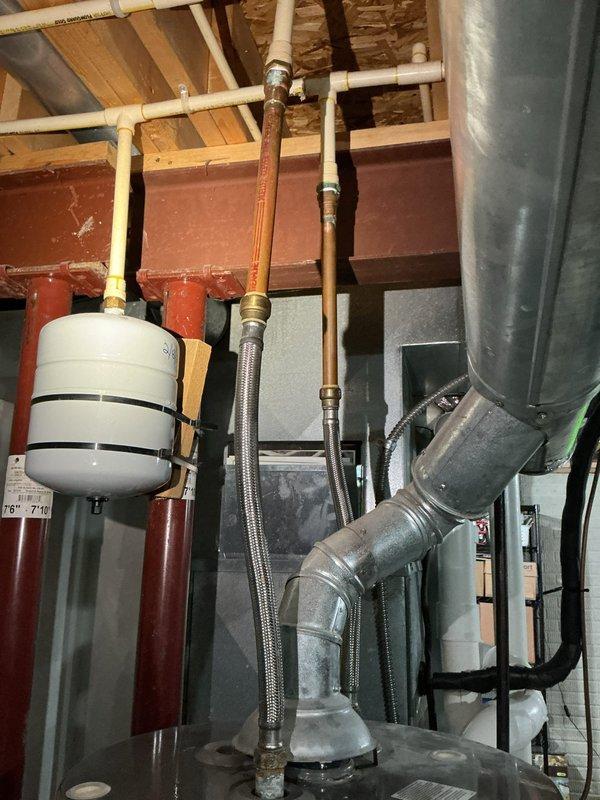 Responded to service call for leaking hot water tank with water accumulation on basement floor. Upon inspection, identified 12-14 year old tanked water heater showing signs of age-related deterioration in a 25-year-old residential property. Examined all visible plumbing connections, including copper supply lines, expansion tank, and associated fittings for signs of active leaking. Assessed water heater condition, noting oxidation on copper piping and evaluating overall system integrity. Documented mechanical system configuration including ductwork, PVC drainage, and braided stainless steel connectors. No structural damage to surrounding area was observed despite water presence on concrete floor.