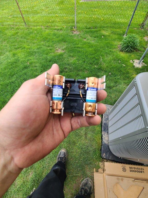 Completed installation of outdoor condensing unit as part of previously scheduled winter AC system installation. Replaced dual fuses in exterior disconnect box and verified proper electrical connections. Confirmed all refrigerant lines, electrical wiring, and condensate drainage properly connected between indoor furnace coil and outdoor condenser unit, with system now fully operational for cooling season.