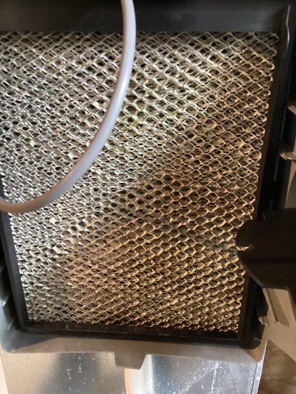 Completed recurring preventive maintenance inspection on HVAC system. Inspected and documented condition of air filtration components, including standard pleated air filter showing moderate dust accumulation and evaporative cooling pad exhibiting mineral deposits and discoloration from extended use. System components photographed for maintenance records.