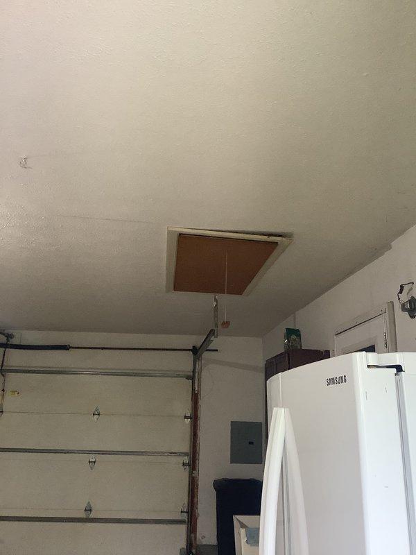 Provided estimate for replacement of 1990's era residential air conditioning system utilizing obsolete R22 refrigerant. Existing outdoor condenser unit shows significant age-related wear and deterioration with accumulated debris on fan grill and weathered exterior casing. Indoor air handler located in garage attic space accessed via ceiling panel. Due to phaseout of R22 refrigerant and age of equipment exceeding typical service life, recommended complete system replacement with modern high-efficiency unit using current refrigerant technology.