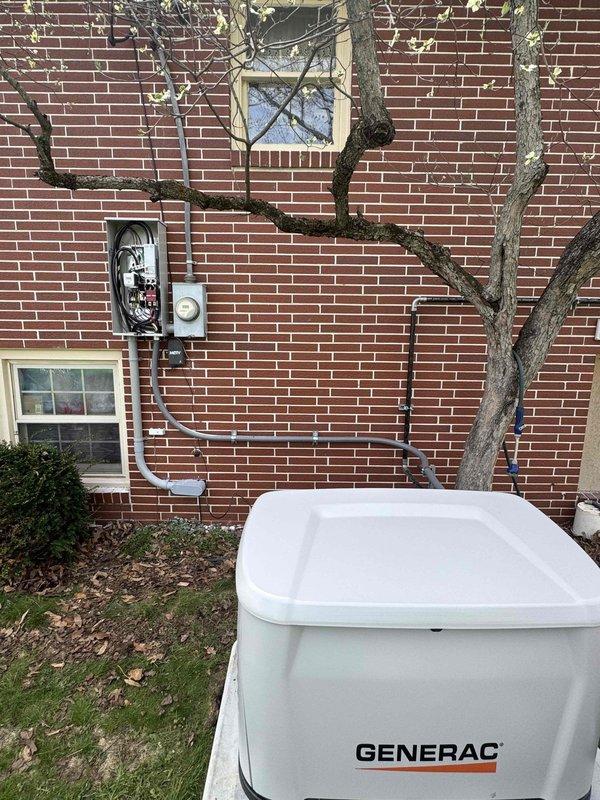 Completed installation of a 24 KW Generac standby generator with 200-amp automatic transfer switch at residential property. Installed generator unit on concrete pad adjacent to brick exterior wall with proper clearances maintained. Ran 15 feet of gas piping from existing gas line to generator unit, ensuring all connections met code requirements. Mounted transfer switch in interior location with appropriate electrical connections to main service panel and generator. Wired transfer switch to monitor utility power and automatically engage generator during power outages. All electrical conduit runs were secured to building exterior and routed to minimize exposure. Tested generator startup sequence, transfer switch operation, and verified proper load transfer between utility and generator power. System commissioned and confirmed operational for automatic backup power functionality.
