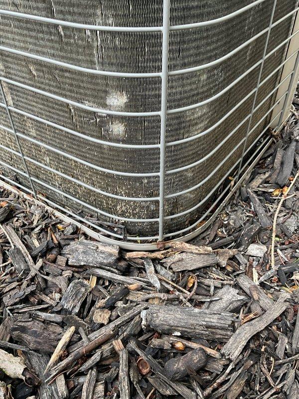 Responded to no-cooling call on 20+ year old air conditioning system. Upon arrival, found evaporator coil frozen with ice accumulation and outdoor condenser fan motor inoperative. Inspected indoor furnace unit and confirmed restricted airflow contributing to freeze-up condition. Examined outdoor condenser unit and verified fan motor failure preventing proper heat rejection. Documented equipment condition with photographs showing aged system components, dirty condenser coils with debris accumulation in mulch bed area, and compromised airflow through protective guard. Advised customer of system age, failed components, and benefits of system replacement options including maintenance plan coverage.