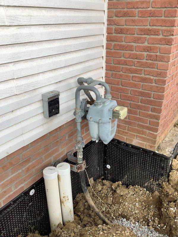 Responded to service call for gas meter that was removed during wall maintenance and became twisted during reinstallation. Upon arrival, assessed the exterior-mounted natural gas meter installation and confirmed the meter assembly had been improperly repositioned. Carefully untwisted the gas meter piping to restore proper alignment and orientation of the meter body and connecting lines. Reattached and secured the meter assembly to the exterior wall mounting bracket, ensuring all pipe connections were properly aligned with both the building supply lines and the curved riser pipes. Verified all connections were secure and the meter was level and stable on its mounting stand. Inspected the complete installation including the horizontal supply piping and vertical connections to confirm proper positioning and no stress on joints or fittings.