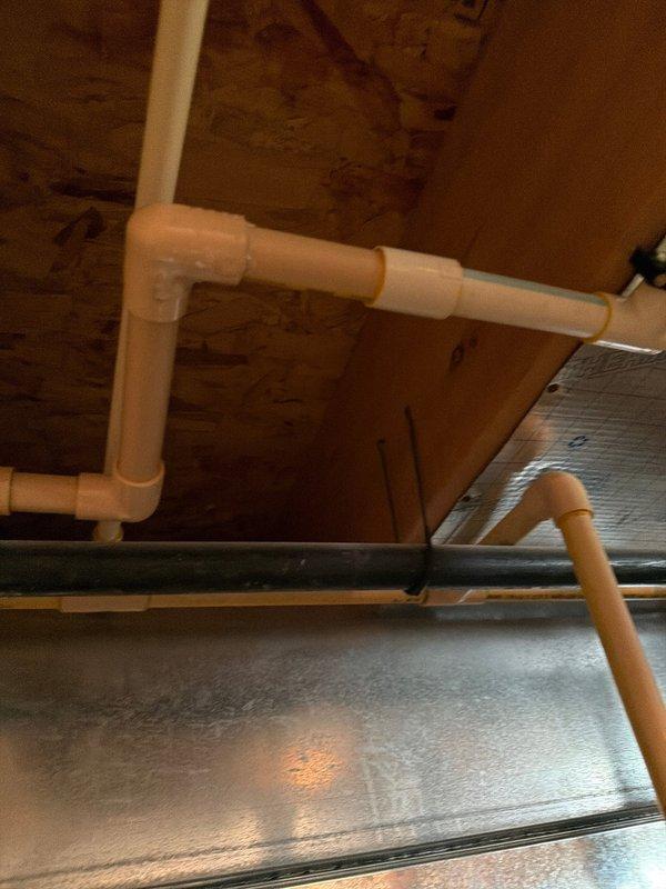 Responded to service call for high-pitched noise emanating from upstairs bathroom shower and faucet fixtures in 26-year-old residential property. Upon inspection, accessed crawl space and basement utility areas to trace water supply lines and identify source of whistling sound. Examined plumbing system including copper supply lines, PVC drainage configuration, and fixture connections throughout affected bathroom. Diagnosed noise as water hammer or resonance within aging supply piping, likely caused by partially restricted flow or loose pipe mounting. Inspected pressure regulation system and verified no leaks, blockages, or pressure irregularities present. Documented existing plumbing infrastructure configuration with photographic evidence showing overhead pipe routing in attic space and basement copper supply line arrangement. Provided recommendations for resolution including potential installation of water hammer arrestors, securing loose pipe sections, or adjusting water pressure if 