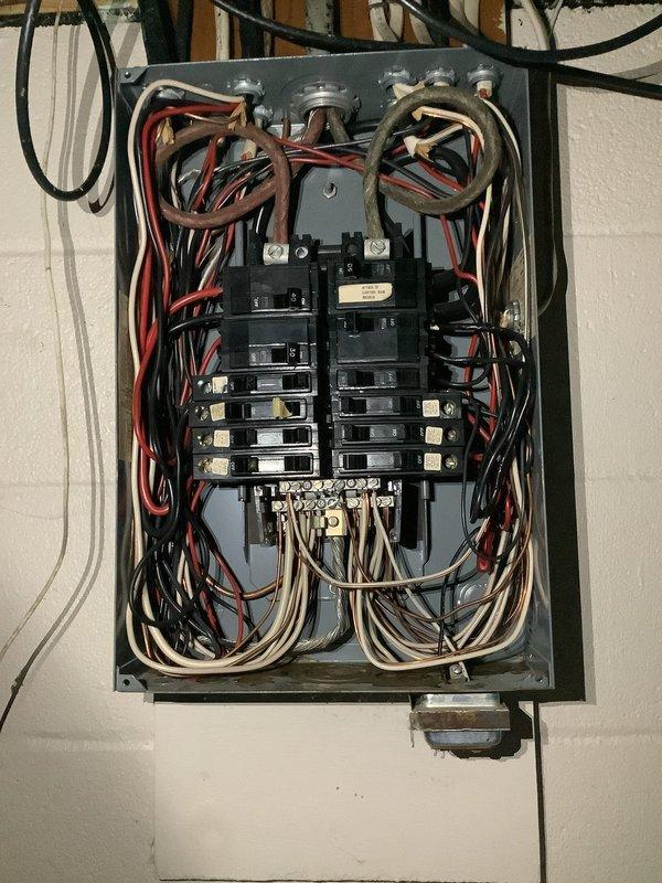 Responded to service call for non-operational electric tankless water heater in 50-year-old residence. Upon arrival, confirmed complete loss of electrical power to the unit. Conducted comprehensive diagnostic assessment of the electrical system, inspecting the main service panel and circuit breaker configuration. Examined interior panel components, including dual-column breaker arrangement, conductor terminations, and neutral/ground bus bar connections. Verified proper wire routing and assessed condition of red, black, and white insulated conductors throughout the distribution panel. Inspected exterior electrical service equipment, including utility meter installation and incoming service connections. Identified and resolved electrical supply issue affecting tankless water heater operation. Restored power to unit and verified proper functionality. Documented electrical panel conditions and exterior service equipment with photographs for service records.