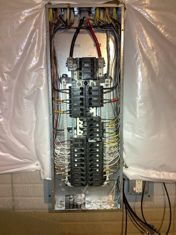 Conducted on-site assessment for electrical panel replacement in residential property undergoing renovation. Evaluated existing breaker box configuration, which contained dual rows of circuit breakers with multiple branch circuits serving the dwelling. Documented current panel condition, wire routing, and main service connections to provide accurate replacement quote. Noted installation location features exposed wall framing with OSB sheathing and protective plastic sheeting in work area, indicating active construction environment requiring coordination with ongoing renovation work.