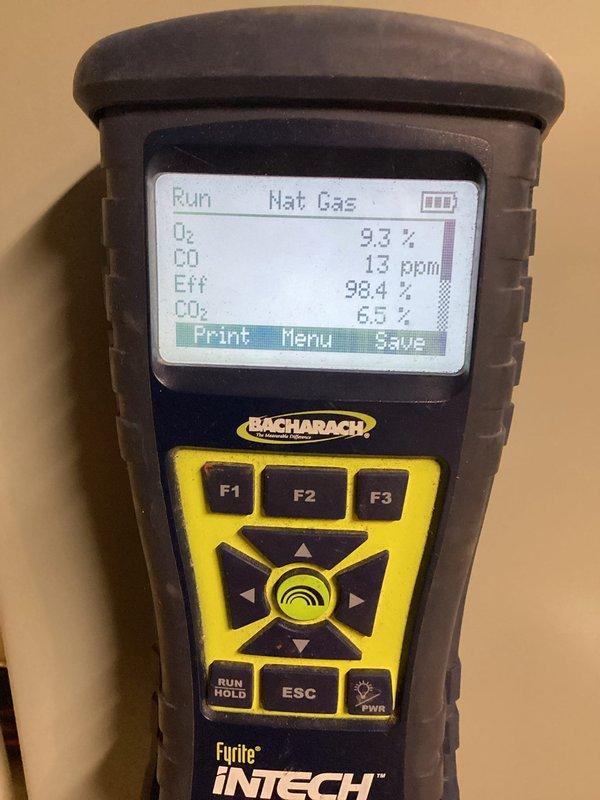 Completed heating system tune-up and performance evaluation. Performed combustion analysis on natural gas furnace using Bacharach Fyrite InTech analyzer, confirming optimal operating parameters with 98.4% efficiency, O₂ at 9.3%, CO at 13 ppm, and CO₂ at 6.5%. Measured electrical amperage draw at 5.16 amps using digital clamp meter to verify proper motor operation and system performance within manufacturer specifications.