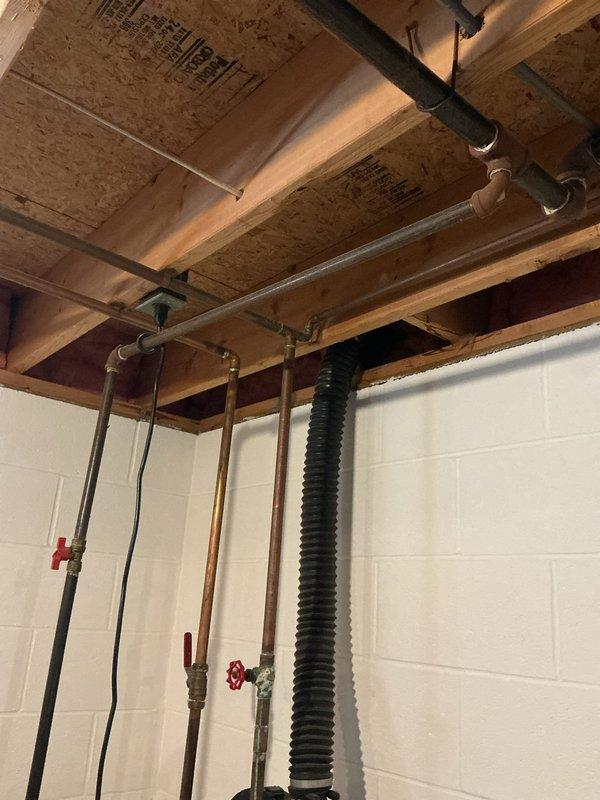 Conducted site assessment in basement utility area to provide estimate for installing hot water supply lines and natural gas lines for pool equipment. Evaluated existing plumbing infrastructure including copper water supply lines with shut-off valves and current gas piping configuration. Documented routing requirements through exposed floor joists and concrete block foundation wall to determine optimal path for new piping runs to exterior pool location. Photographed existing utility connections, available access points, and structural considerations for proposed installation work.