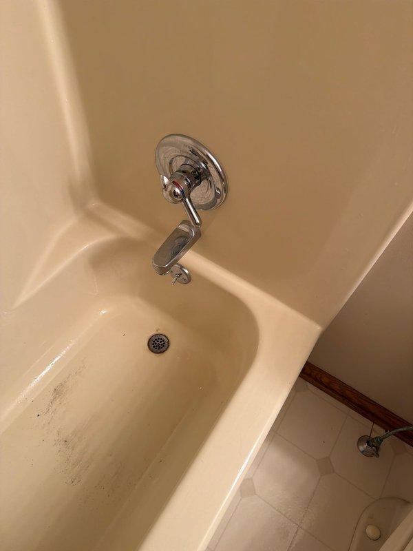 Responded to service call for multiple faucet installations and plumbing fixture work. Installed chrome utility sink faucet with dual handles and arched spout on white basin in utility area, addressing existing rust staining and drainage concerns. Serviced bathtub faucet assembly and spout in bathroom with cream-colored fiberglass surround, resolving reported leak issue. Documented existing mineral deposits and surface staining on fixtures for customer awareness.