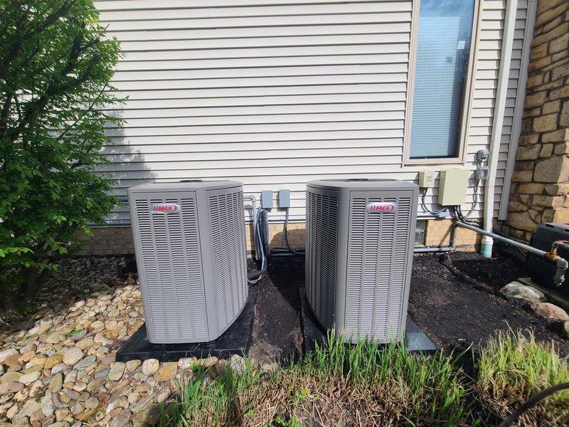 Completed installation of two Lennox outdoor condensing units with corresponding evaporator coils for a dual-zone residential HVAC system. Units were positioned side by side on vibration-dampening rubber pads against the exterior wall, with copper refrigerant lines and electrical conduits properly routed and secured to the building. Installed DiversiTech disconnect boxes with appropriate fusing for each unit to meet electrical code requirements. All refrigerant lines were brazed, insulated, and tested for leaks. System was evacuated, charged to manufacturer specifications, and tested for proper operation. Installation includes proper drainage provisions and meets all applicable building and electrical codes.