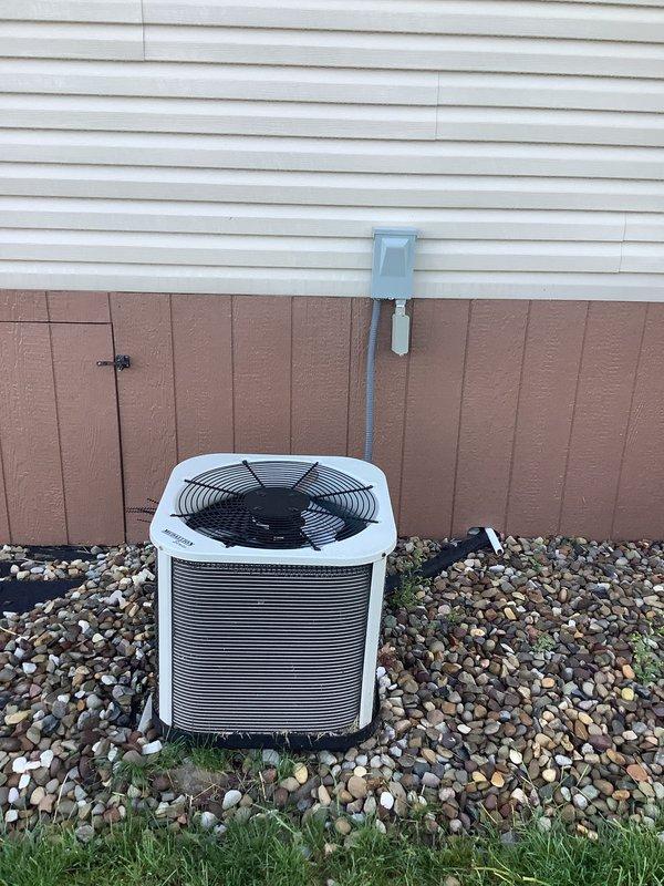 Completed installation of new air conditioning system with evaporator coil for mobile home application. Installed outdoor condensing unit on prepared rock bed with proper clearances, ran refrigerant lines and electrical conduit up exterior wall to weatherproof disconnect box, and replaced fused disconnect with 20-amp fuses. System tested and operational upon completion.