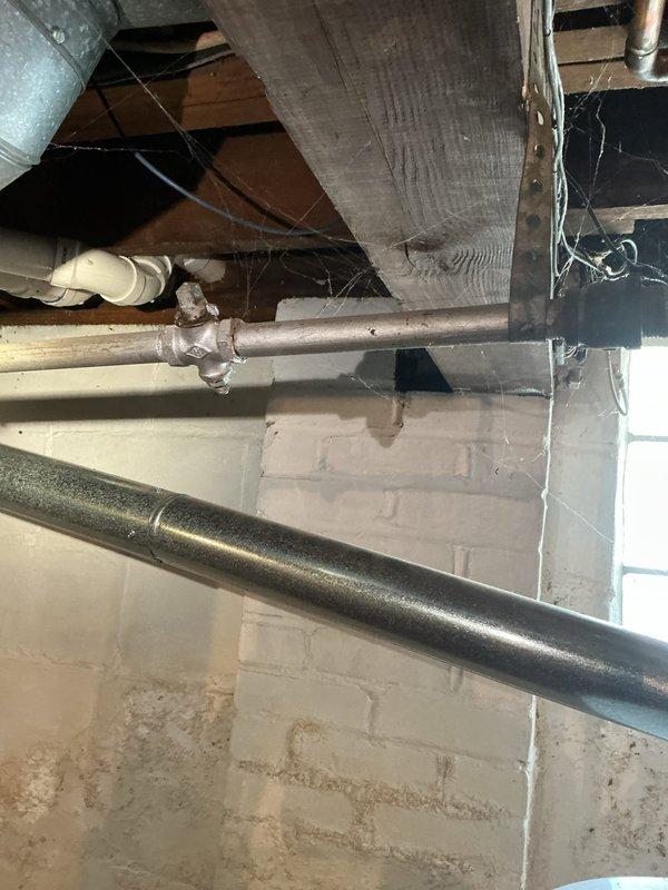 Responded to service call for 18-year-old Bradford White 40-gallon natural gas water heater (Model MI40T6FBN) experiencing leaks from two separate locations on the tank. Upon inspection, documented the condition of the unit installed in basement crawl space area and confirmed active leaking from the tank body, which is typical of tank failure due to internal corrosion at this age. Photographed the water heater specifications and installation environment showing the unit's connection to existing gas and water supply lines, as well as the surrounding utility infrastructure including copper piping, black gas line, and PVC drainage.