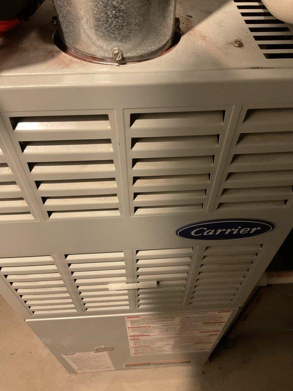 Responded to no-heat call on 25-year-old Carrier furnace. Upon arrival, found unit would not maintain flame after manual reset - pilot light would ignite then extinguish shortly after. Diagnosed intermittent flame sensor failure causing safety lockout on aging system. Documented existing equipment condition with photos showing furnace cabinet, internal components including blower assembly, gas valve, and control wiring.