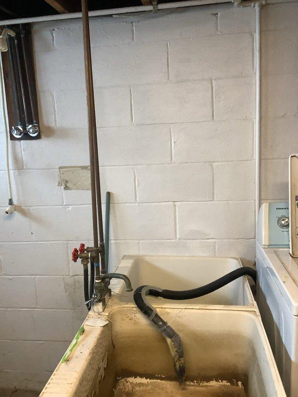 Responded to service call for estimate on new water line installation at residential property built in 1956. Conducted thorough assessment of existing plumbing infrastructure in basement utility area. Inspected aging copper supply lines, shut-off valves, and current water service configuration. Documented condition of existing utility sink showing significant age-related staining and deterioration. Evaluated routing options for new water line installation through unfinished basement space with exposed floor joists and concrete block foundation walls. Assessed accessibility for pipe installation considering existing HVAC ductwork, electrical panel placement, and structural components. Photographed current plumbing system layout and utility room conditions to support estimate preparation. Identified optimal path for new water service line to minimize disruption while ensuring code compliance and proper installation clearances.