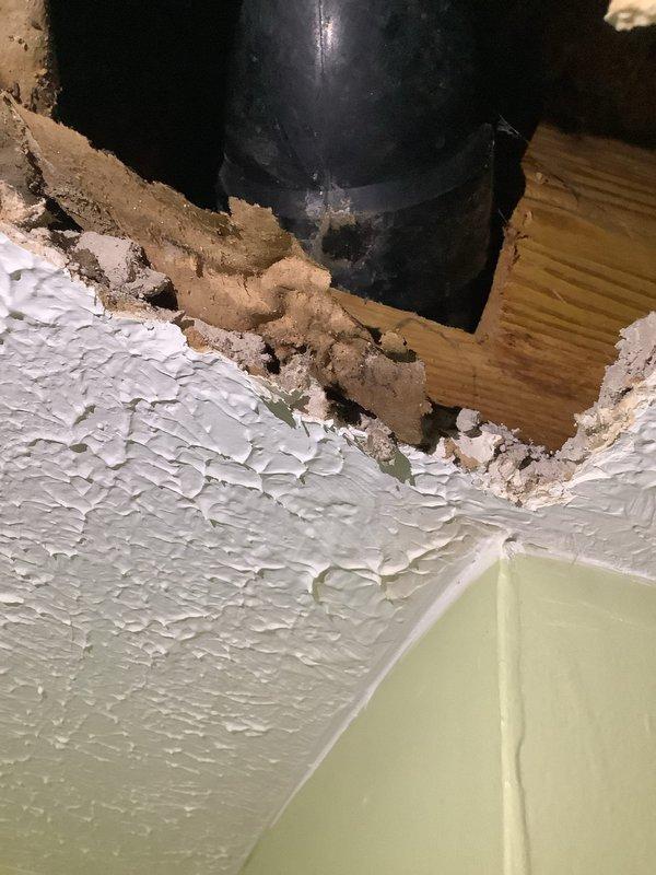 Responded to water leak originating from bathroom and penetrating through ceiling into kitchen area of 60-year-old residential property. Upon inspection, identified significant ceiling deterioration around plumbing penetration point with extensive water damage, including cracked and peeling textured ceiling material, exposed substrate, and compromised structural elements. Assessed bathroom plumbing fixtures and flooring condition. Documented damage with photographs showing deteriorated ceiling section with black pipe penetration and extent of material failure. Leak source identified and evaluated for repair recommendations given age of home's plumbing system.