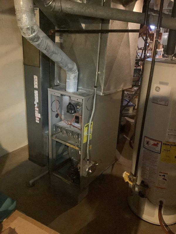 Completed full HVAC system installation including an 80% efficiency furnace and air conditioning unit for an 858 square foot residential property. The AC condenser was positioned at the rear of the home per the site plan, with the furnace installed in the basement mechanical room alongside existing water heating equipment. New flexible ductwork was installed and connected to the furnace with proper insulation, and all gas connections were secured with appropriate shut-off valves for safety compliance.