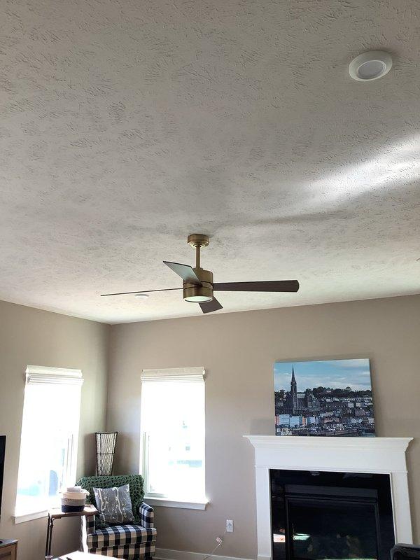 Replaced existing chandelier with a six-arm brushed nickel fixture featuring candle-style bulbs in residential room. Installed ceiling fan with integrated light fixture and dark wooden blades into builder-wired junction box in separate room, ensuring proper mounting and electrical connections for both fixtures.