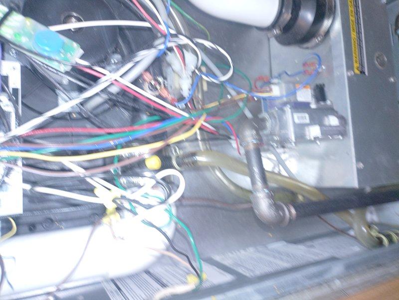 Responded to service call for furnace emitting burning odor with visible damaged component. Upon inspection, accessed unit interior and identified compromised electrical component on control board. Documented existing wiring configuration and component condition with photographs showing extensive wire harness network, control board connections, and internal mechanical assembly including blower motor housing and PVC condensate piping. Given household occupant's medical sensitivity to temperature fluctuations, prioritized rapid assessment and provided recommendations for component replacement to restore safe heating system operation.