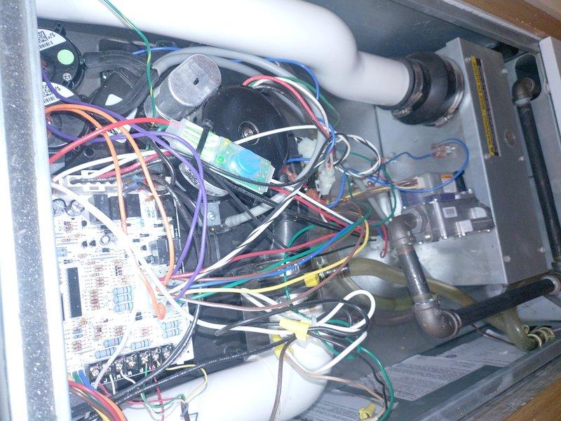 Responded to service call for furnace emitting burning odor with visible damaged component. Upon inspection, accessed unit interior and identified compromised electrical component on control board. Documented existing wiring configuration and component condition with photographs showing extensive wire harness network, control board connections, and internal mechanical assembly including blower motor housing and PVC condensate piping. Given household occupant's medical sensitivity to temperature fluctuations, prioritized rapid assessment and provided recommendations for component replacement to restore safe heating system operation.