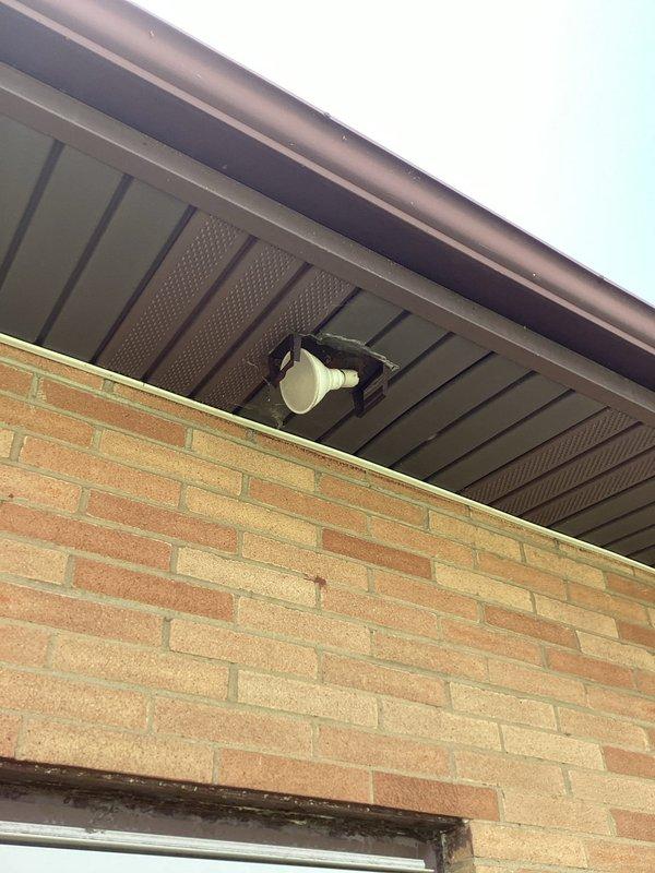 Completed on-site electrical assessment for replacement of three exterior lighting fixtures including motion-activated patio light, side door light, and front door light. Evaluated existing soffit-mounted fixtures on brick and vinyl-sided residential exterior, documented current installations, and provided estimate for fixture replacement work.