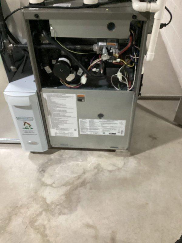 Completed comprehensive AC tune-up service on residential HVAC system. Inspected gas furnace internal components including blower motor assembly, electrical connections, and wiring harnesses; all components found in satisfactory operating condition. Observed moisture staining on concrete floor near furnace base indicating potential condensation drain issue requiring future monitoring. Examined outdoor condenser unit and found air filter severely clogged with dirt, dust, and debris accumulation; filter replacement strongly recommended to restore proper airflow and system efficiency.