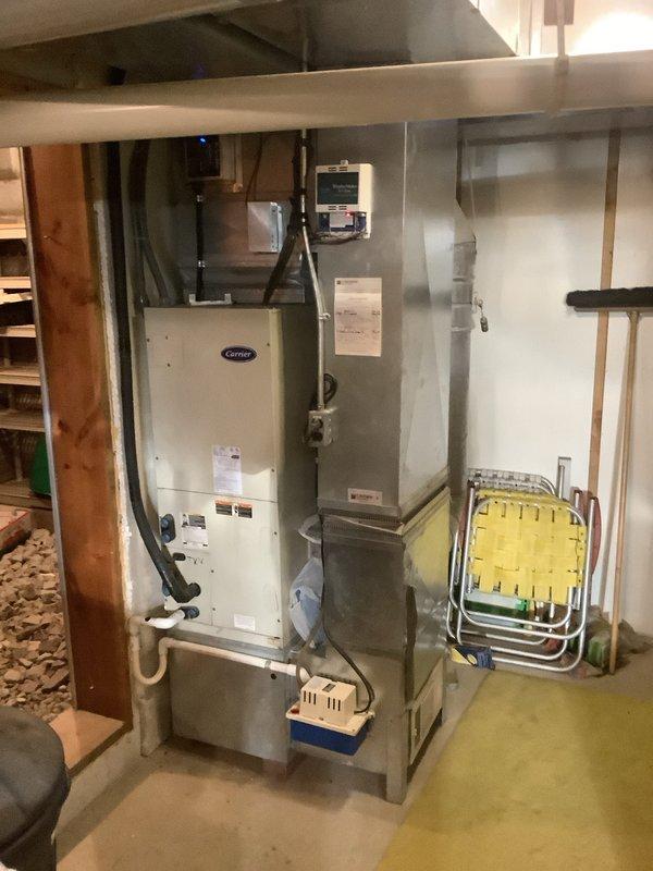Completed full HVAC system installation including Carrier air handler with integrated heat strips, heat pump condenser unit, and associated ductwork. Air handler was mounted in basement utility area with proper electrical connections and supply/return plenum installations. Exterior heat pump unit was positioned on concrete pad against home exterior with refrigerant lines run through wall penetration, electrical disconnect installed, and unit leveled and secured. System was pressure tested for leaks, evacuated, charged to manufacturer specifications, and startup procedures completed with all safety controls verified operational.