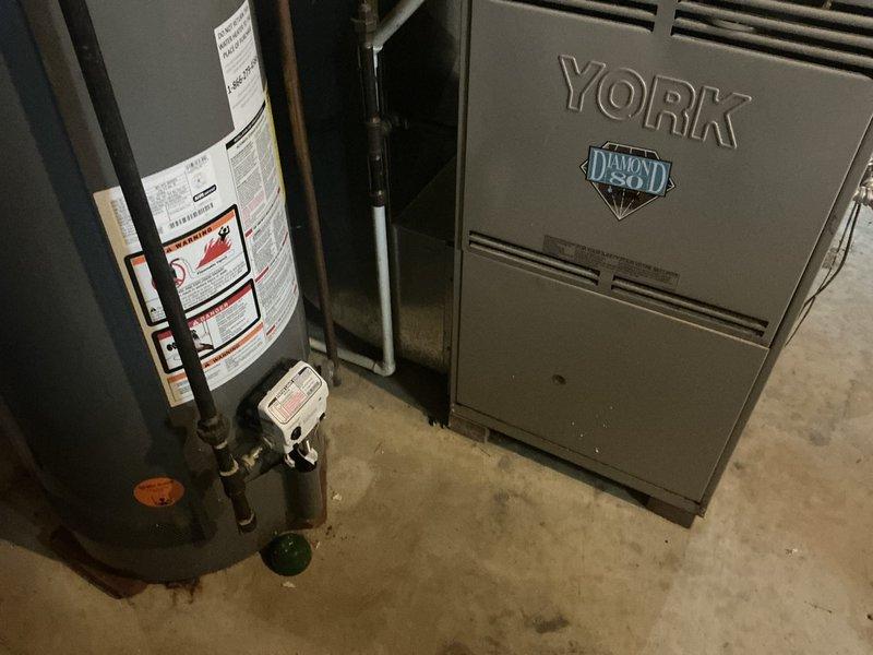 Completed furnace replacement estimate for residential HVAC system. Evaluated existing York Diamond 80 furnace installation in basement utility area, documented current equipment configuration including PVC venting connections, ductwork interface, and proximity to water heating equipment. Photographed unit specifications, ventilation components, and mechanical room layout to provide comprehensive assessment for replacement options.
