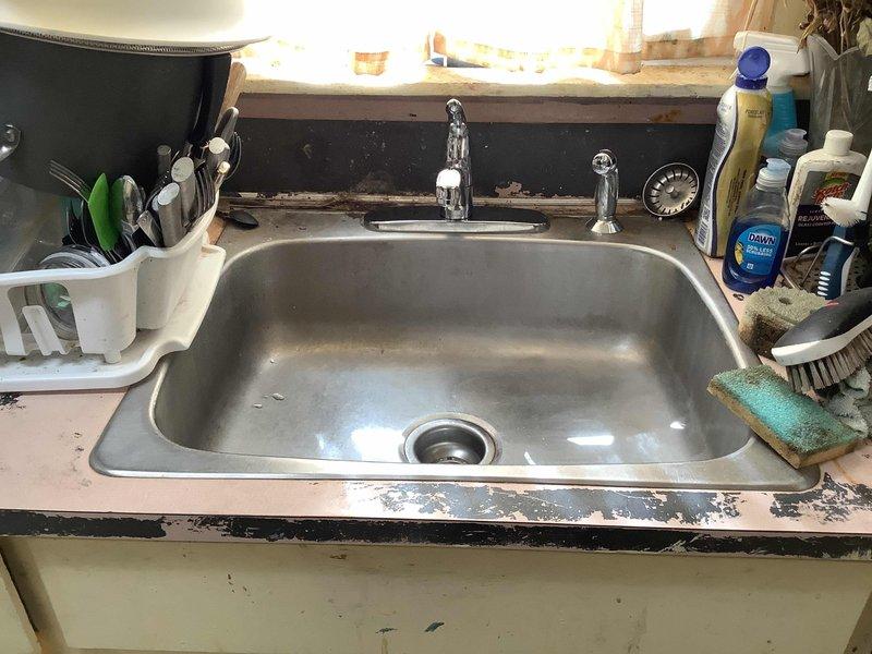 Replaced kitchen faucet with side spray unit and basement shower faucet assembly. The basement installation required replacement of the Central Brass 7223-A fixture due to deteriorated riser pipe that had rotted out. Parts were ordered for will call pickup, and photographic documentation was captured showing the existing conditions of both the kitchen sink area and basement plumbing installation prior to repair completion.