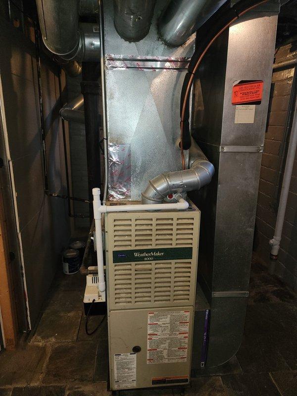Completed installation of new residential air conditioning system with matching evaporator coil. Outdoor condensing unit was mounted on exterior wall with proper refrigerant line sets, electrical disconnect, and conduit connections routed through vinyl siding, while indoor evaporator coil was installed on existing WeatherMaker 8000 furnace with appropriate ductwork modifications and condensate drainage. System was tested and confirmed operational with all components properly secured and connected to manufacturer specifications.