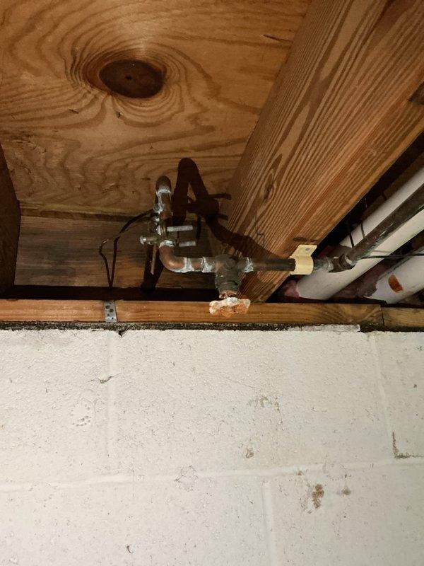 Responded to service call for two leaking shut-off valves in basement that control exterior hose bibs. Upon inspection, located copper pipe assembly with shut-off valves mounted to floor joists near exterior wall penetrations. Identified active leaks at valve packing nuts and compression fittings. Tightened packing nuts and verified proper valve operation. Tested both shut-off valves under pressure to confirm leak repair was successful and no further dripping occurred.