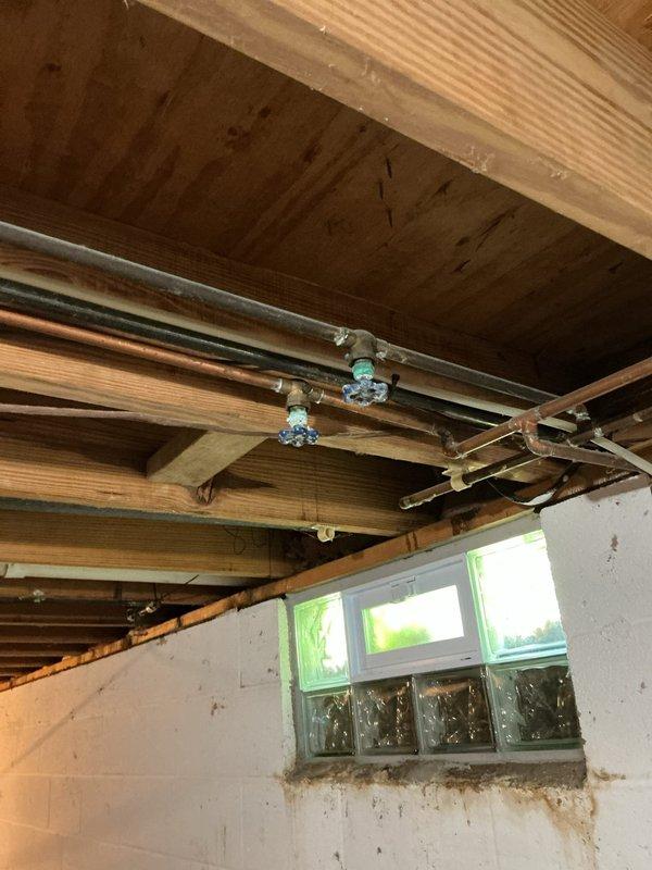 Responded to service call for two leaking shut-off valves in basement that control exterior hose bibs. Upon inspection, located copper pipe assembly with shut-off valves mounted to floor joists near exterior wall penetrations. Identified active leaks at valve packing nuts and compression fittings. Tightened packing nuts and verified proper valve operation. Tested both shut-off valves under pressure to confirm leak repair was successful and no further dripping occurred.