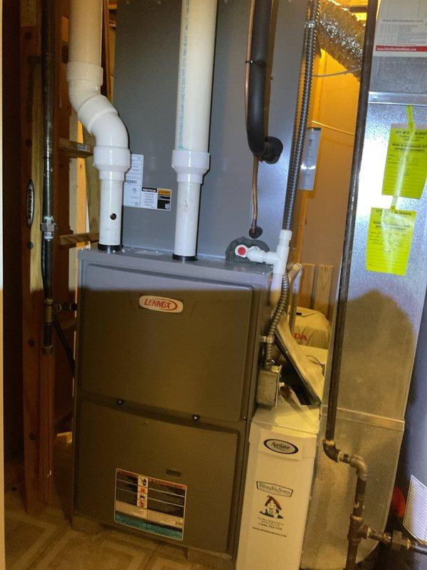 Completed scheduled BS-MVP cooling and heating maintenance visit on residential HVAC system. Performed comprehensive inspection of Lennox furnace unit in basement mechanical room, verifying proper operation of high-efficiency exhaust and intake PVC venting system. Inspected outdoor condensing unit, noting algae and mold growth on exterior casing requiring cleaning attention. Documented equipment condition through photographic records showing both indoor furnace installation and outdoor AC unit placement. All major system components assessed for proper function and seasonal readiness.