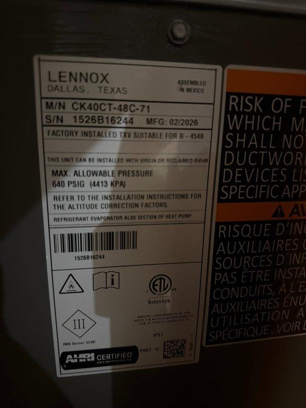 Completed installation of new Lennox air conditioning system including outdoor condenser unit (Model CK40CT-48C-71, Serial 1526B16244) and evaporator coil. Unit is factory-rated for R-454B refrigerant with maximum operating pressure of 640 PSIG. Mounted condenser on ground-level pad against exterior wall of residential structure with horizontal vinyl siding. Installed refrigerant line set with gray insulation running vertically from condenser to indoor coil penetration point. Connected electrical service through wall-mounted disconnect box with proper conduit installation. Verified all electrical connections meet code requirements and system is properly grounded. Tested unit operation and confirmed proper refrigerant charge and system functionality.