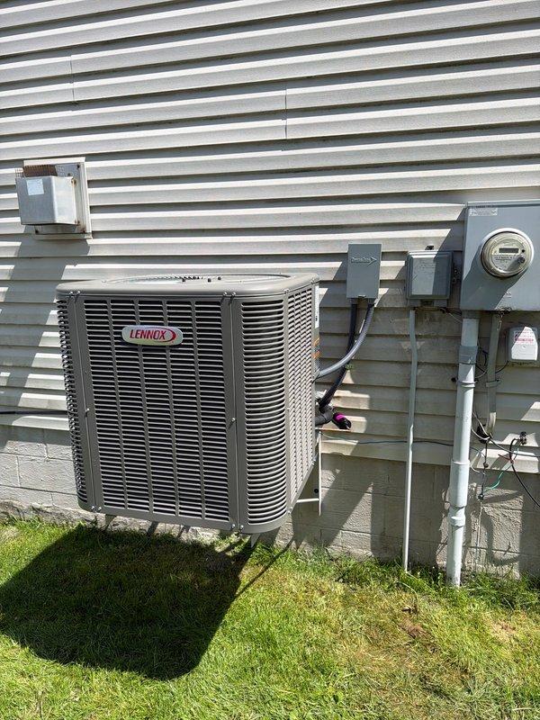 Completed installation of new Lennox air conditioning system including outdoor condenser unit (Model CK40CT-48C-71, Serial 1526B16244) and evaporator coil. Unit is factory-rated for R-454B refrigerant with maximum operating pressure of 640 PSIG. Mounted condenser on ground-level pad against exterior wall of residential structure with horizontal vinyl siding. Installed refrigerant line set with gray insulation running vertically from condenser to indoor coil penetration point. Connected electrical service through wall-mounted disconnect box with proper conduit installation. Verified all electrical connections meet code requirements and system is properly grounded. Tested unit operation and confirmed proper refrigerant charge and system functionality.