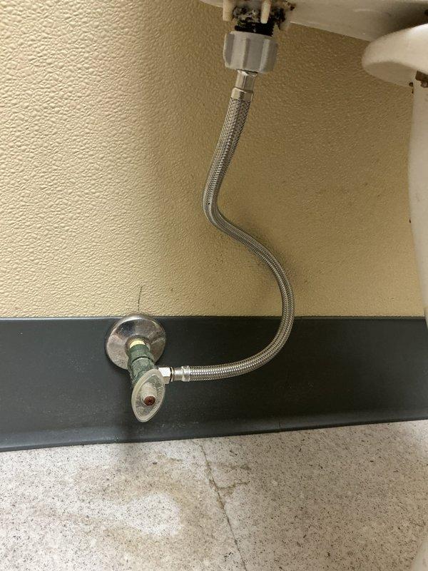 Responded to report of leaking shut-off valve in first stall of ladies restroom. Inspected angle stop valve and braided supply line connection serving toilet fixture. Replaced faulty shut-off valve assembly with new chrome-plated angle stop, installed new braided stainless steel supply line, and tested connections under pressure to verify leak was resolved and proper operation restored.