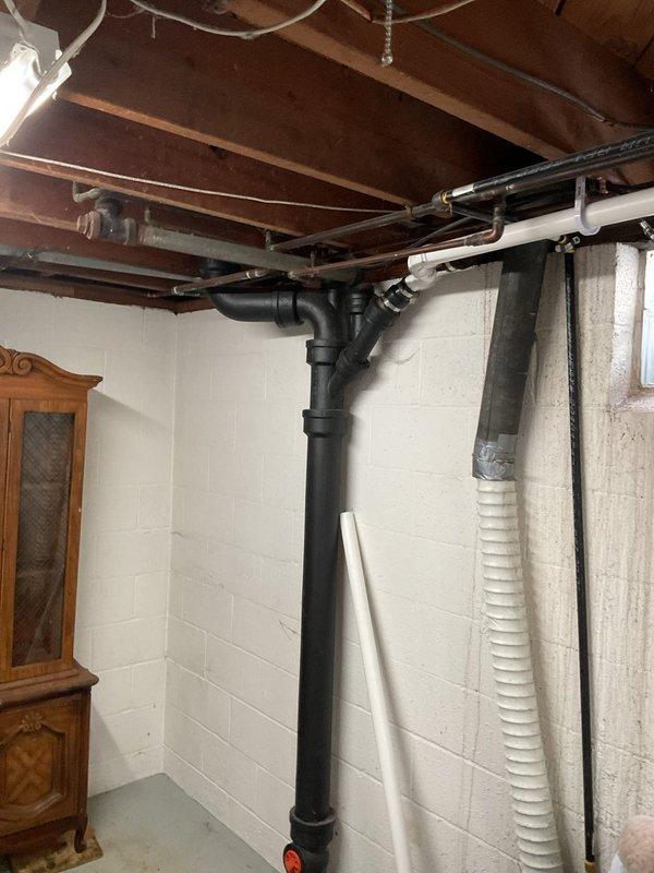 Responded to main drain backup in basement. Located cleanout access point on vertical black PVC drainage stack. Cleared obstruction from main sewer line using appropriate drain cleaning equipment. Verified proper drainage flow restored throughout system. Inspected visible plumbing infrastructure including drainage pipes and fittings to ensure no additional issues present. System tested and confirmed operational with no further backup occurring.