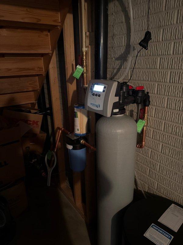 Installed complete water treatment system including city water softener with digital control head and whole home filtration unit with clear canister housing. Mounted all equipment to basement wall framing with proper copper pipe connections and brass fittings. Installed new pressure reducing valve in main water line to regulate incoming water pressure. Replaced existing water heater with new 50-gallon power vent unit, including installation of ball valve and expansion tank for thermal expansion protection. Repaired leaking hot water line located above water heater area using appropriate copper fittings and connections. Connected water softener system to control head with programmed regeneration cycle. Installed pre-filter housing upstream of softener to remove sediment and particulates before water conditioning. Provided initial salt delivery and enrolled system in ongoing salt delivery program for automatic replenishment. Tested all connections for leaks, verified proper water flow th