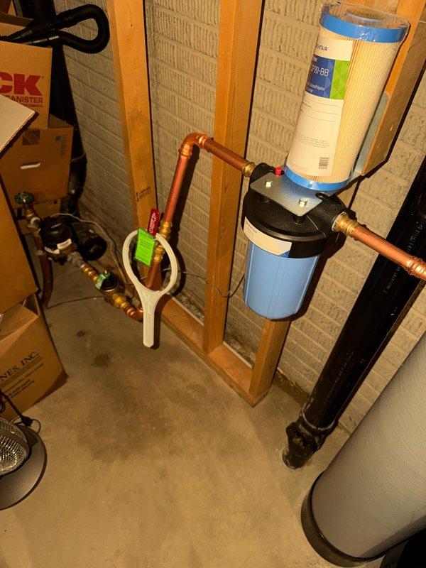 Installed complete water treatment system including city water softener with digital control head and whole home filtration unit with clear canister housing. Mounted all equipment to basement wall framing with proper copper pipe connections and brass fittings. Installed new pressure reducing valve in main water line to regulate incoming water pressure. Replaced existing water heater with new 50-gallon power vent unit, including installation of ball valve and expansion tank for thermal expansion protection. Repaired leaking hot water line located above water heater area using appropriate copper fittings and connections. Connected water softener system to control head with programmed regeneration cycle. Installed pre-filter housing upstream of softener to remove sediment and particulates before water conditioning. Provided initial salt delivery and enrolled system in ongoing salt delivery program for automatic replenishment. Tested all connections for leaks, verified proper water flow th