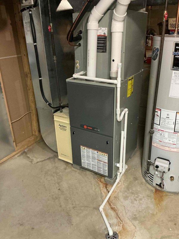Provided comprehensive replacement estimate for existing 12-13 year old Trane furnace system located in basement utility area. Unit was previously diagnosed by technician and documented with detailed photography showing complete HVAC installation including furnace, Aprilaire humidifier, associated ductwork, and PVC venting system. Estimate covers full system replacement with updated equipment to restore reliable heating operation.
