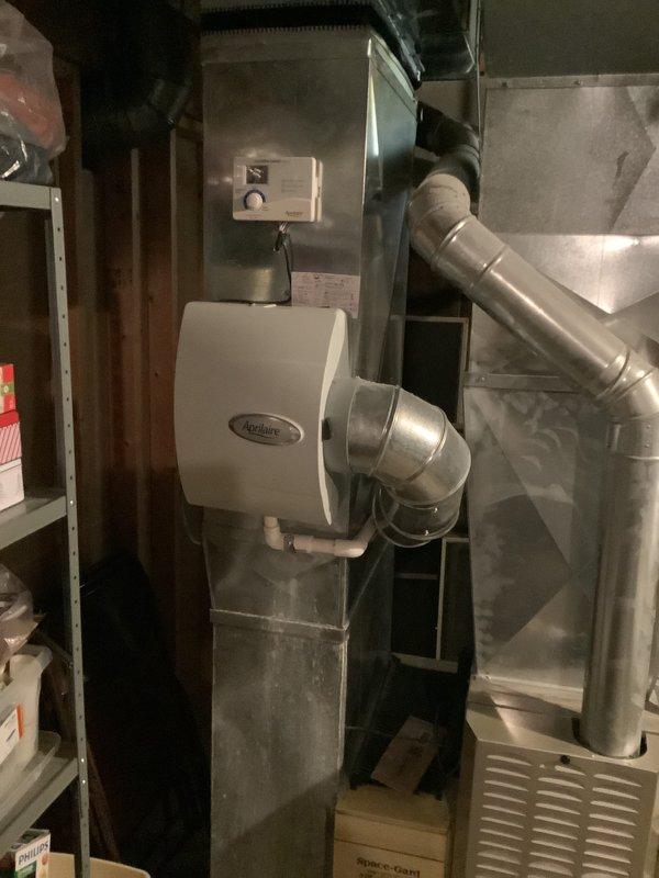 Conducted comprehensive assessment of existing HVAC system including furnace and air conditioning equipment for replacement estimate. Evaluated current installation consisting of Aprilaire humidifier unit with integrated ductwork, main supply plenum, and associated mechanical components in basement utility area. Documented existing system configuration, ductwork layout, electrical controls, and plumbing connections to provide accurate replacement specifications for new furnace and air conditioning system.