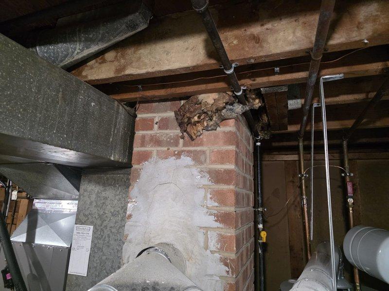 Responded to emergency service call for carbon monoxide concerns following storm damage to furnace flue stack. Upon inspection, found compromised chimney structure with damaged flue connection allowing combustion gases to backdraft into living space instead of properly venting outside. Documented existing conditions showing deteriorated brick chimney with repair patches, damaged ductwork connection to chimney, and debris at chimney crown. Assessed immediate safety hazard and coordinated timing with scheduled carbon monoxide testing. Photographed all affected areas including furnace exhaust connections, chimney structure, and venting system for insurance documentation purposes.