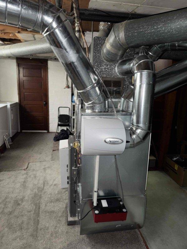 Conducted consultation and assessment of existing ductwork configuration in basement area where customer expressed concerns about low-hanging ducts interfering with ceiling clearance. Documented current HVAC system layout including Aprilaire furnace unit with extensive metallic ductwork network featuring multiple branch connections, flexible insulated ducts, and rigid metal sections. Evaluated feasibility of rerouting ductwork to achieve improved ceiling height and assessed whether mini-split system would be beneficial alternative or supplement to current forced-air setup.