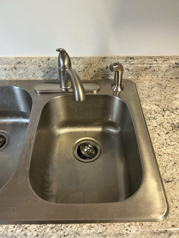 Completed installation of a new Moen Chateau single-handle pull-down kitchen faucet with matching soap dispenser in brushed nickel finish on a double-basin stainless steel sink. Replaced existing supply lines with new braided stainless steel flexible supply hoses and verified all connections for proper operation and leak-free performance.