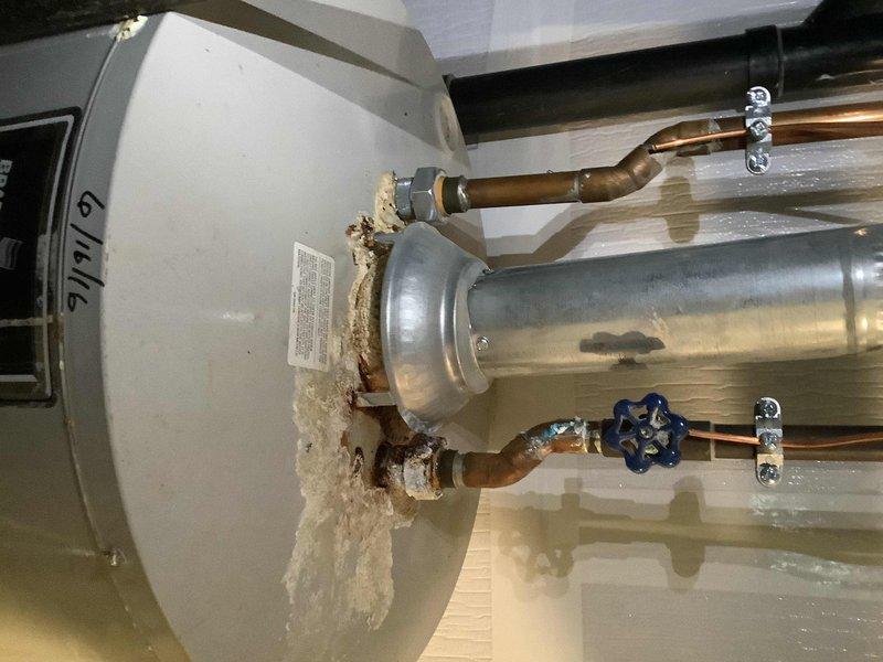 Responded to water leak from aging water heater in 44-year-old residence. Upon inspection, identified deteriorated tank connections with visible corrosion on copper supply lines and compromised pipe fittings showing evidence of previous repair attempts with degraded foam insulation material. Assessed the water heater's overall condition, noting significant age-related wear on plumbing connections and supporting infrastructure. Documented existing conditions including corroded copper piping, aging shutoff valve, and compromised sealing at tank connections for recommended replacement and system upgrade.